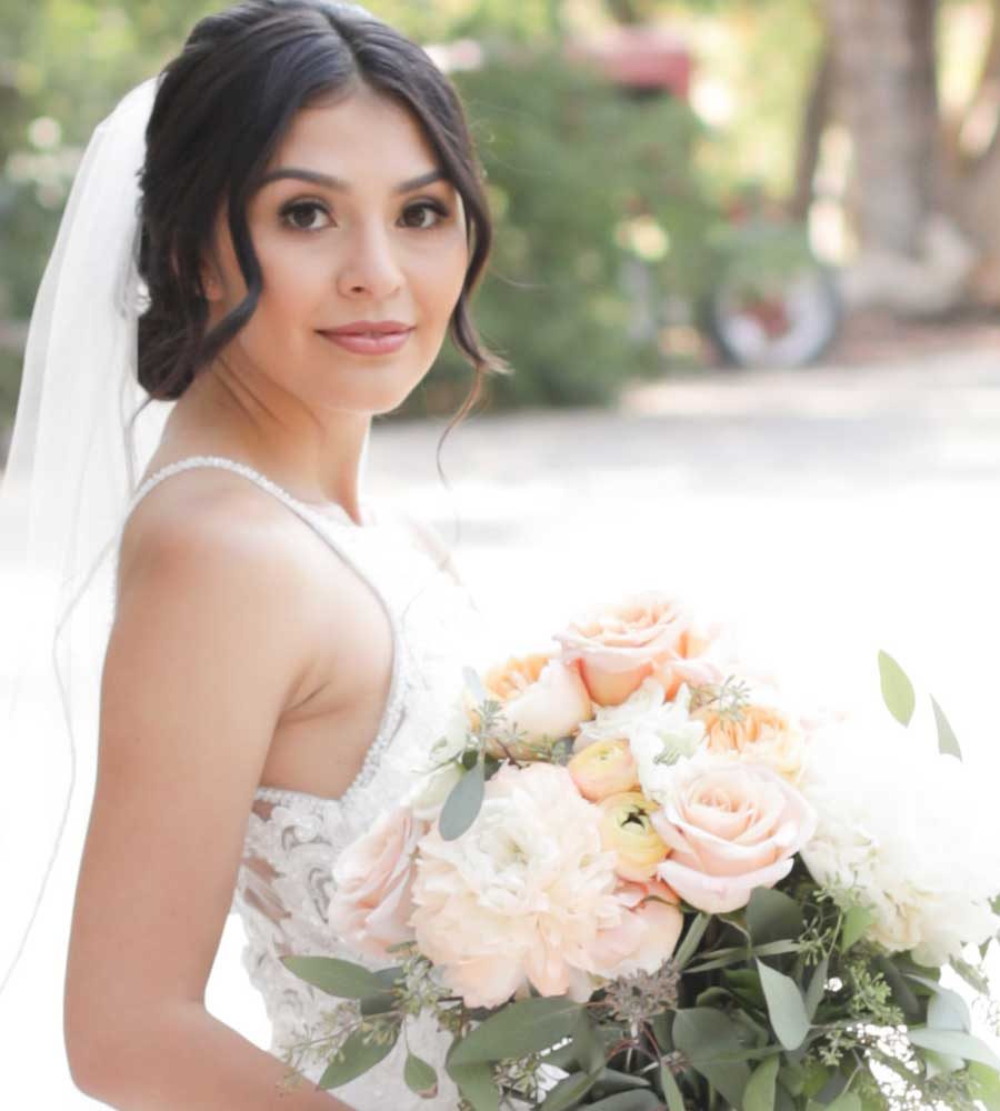 Bride holding a bouquet of peach roses